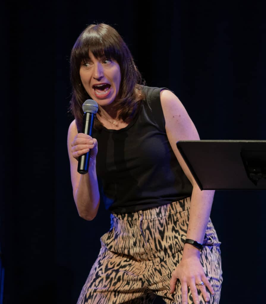 ophira eisenberg on stage with microphone