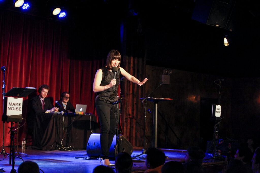 Ophira Eisenberg performing on stage to audience